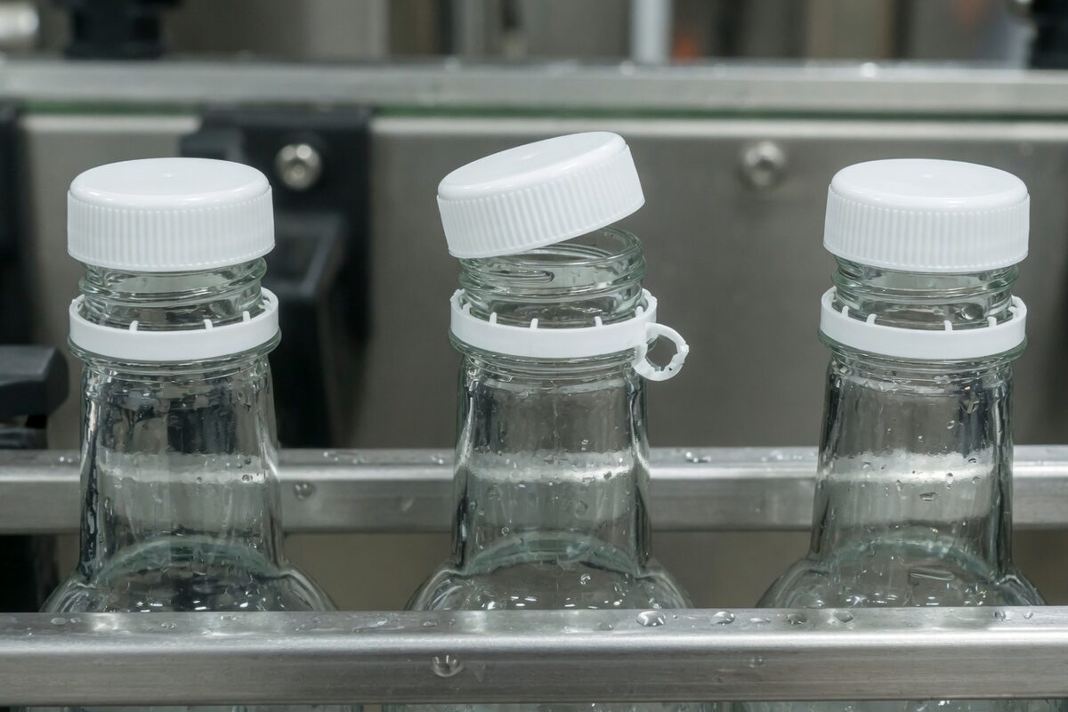 A bottle neck with the cap cocked off the threads and the tamper band torn