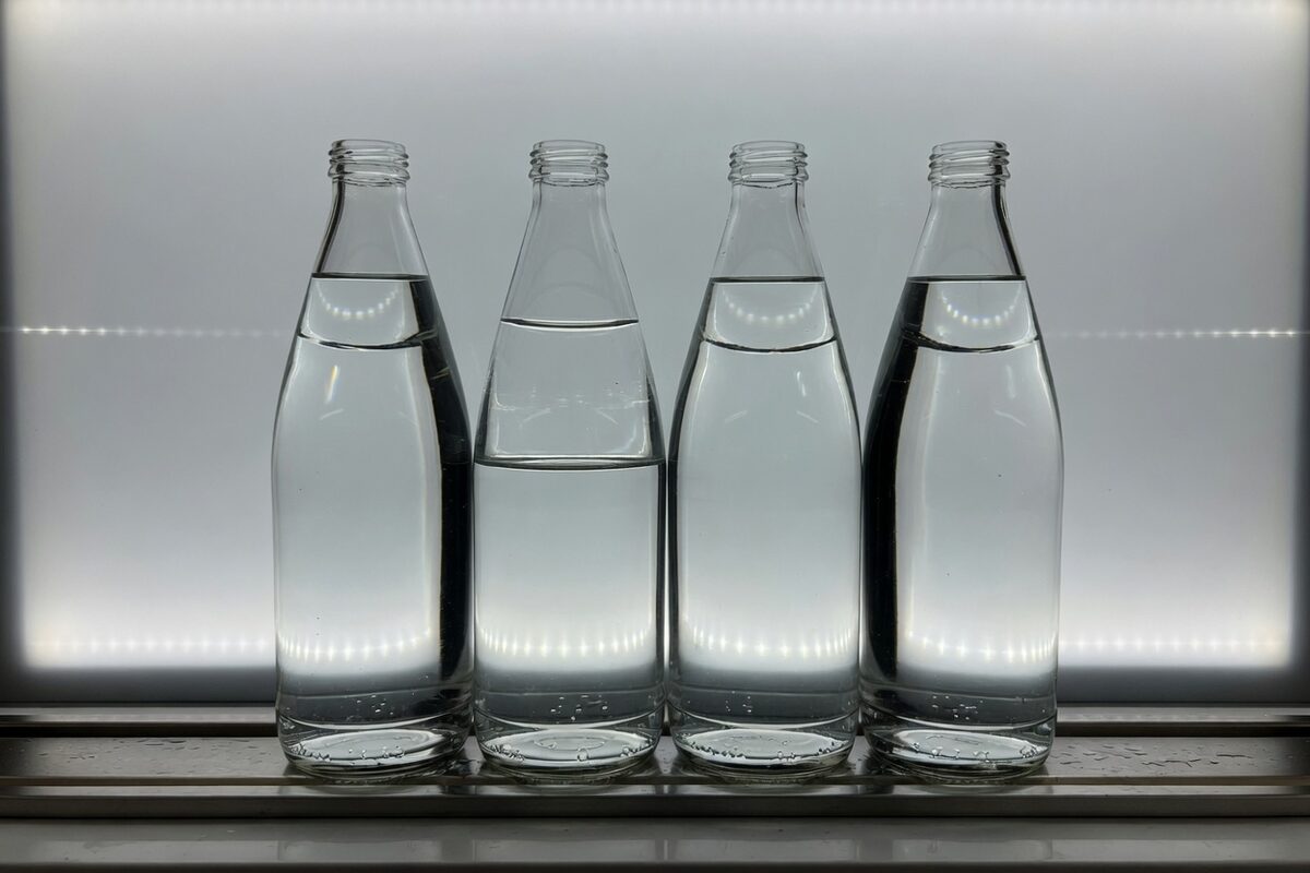 One bottle neck against a gray backlight with the water line below the shoulder