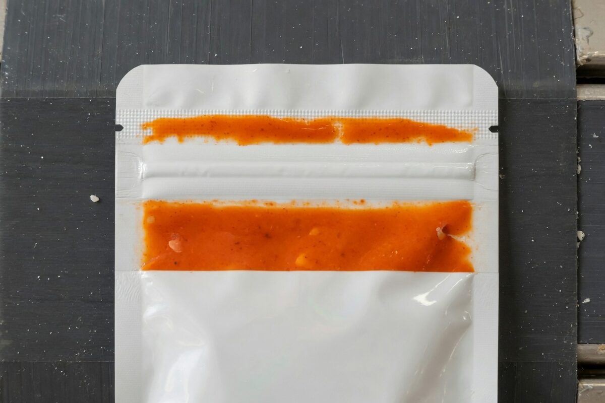 A white pouch with sauce in the top seam