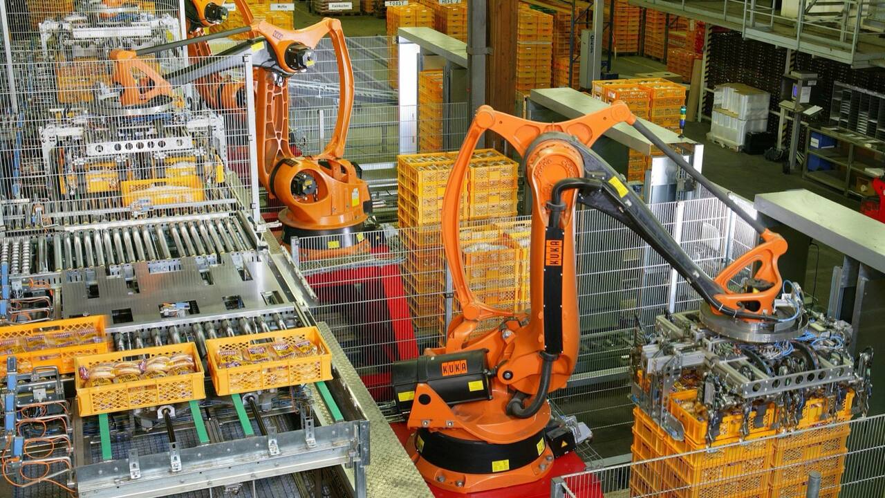 Orange robots palletizing packaged bread in crates on a bakery line